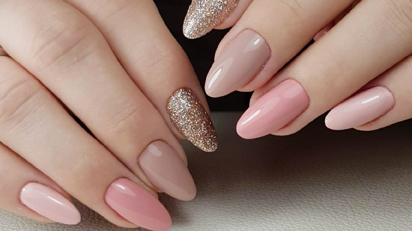 Amandelvormige nagels in zacht nude en roze, met een gouden glitternagel