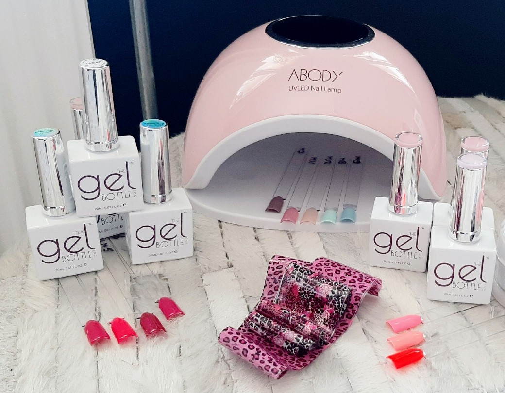 Nathalie's werkplek: een roze UV/LED-lamp, flesjes gellak van The GelBottle, folies en tips op een witte vacht