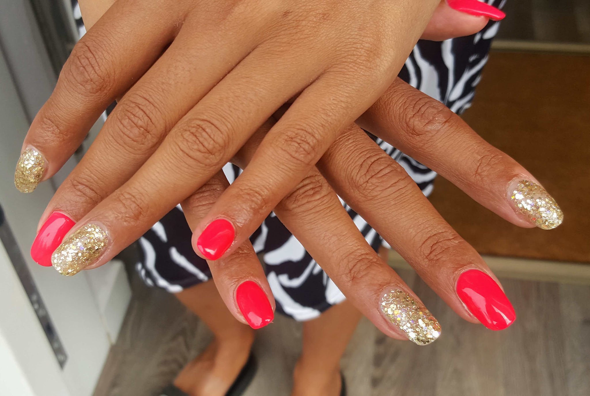 Koraalroze nagels met gouden glitter op de ringvingers